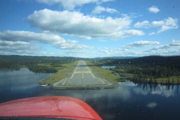 Fra cockpit på finale mot banen på Leirin, med vann og skog rundt