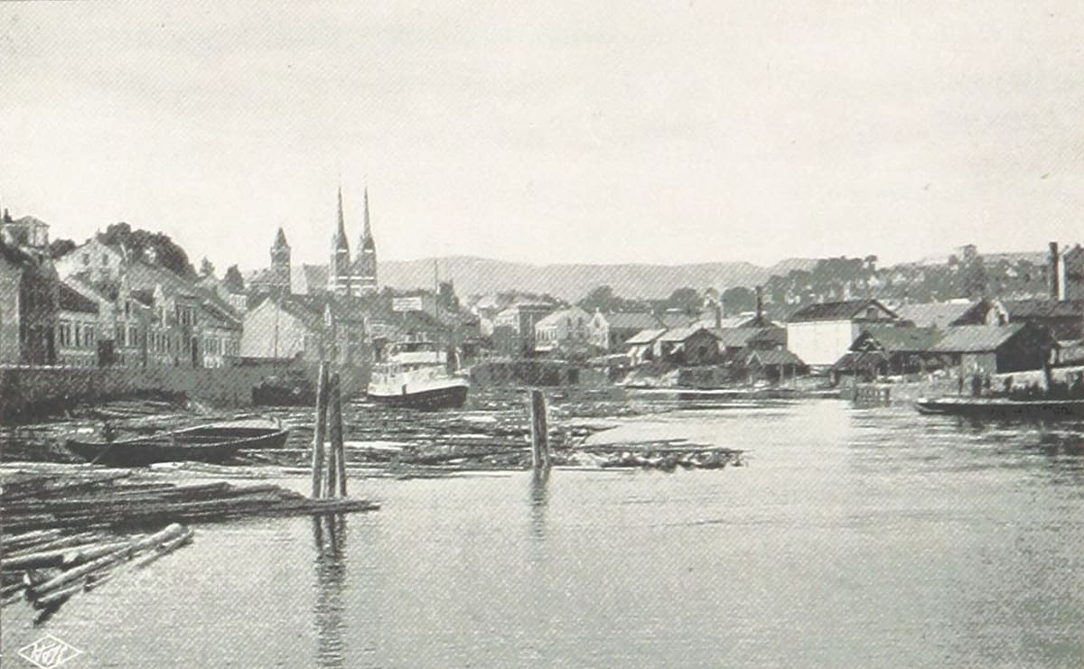 Skien havn i 1896, med tømmerflåter i elva og kirketårnene bak