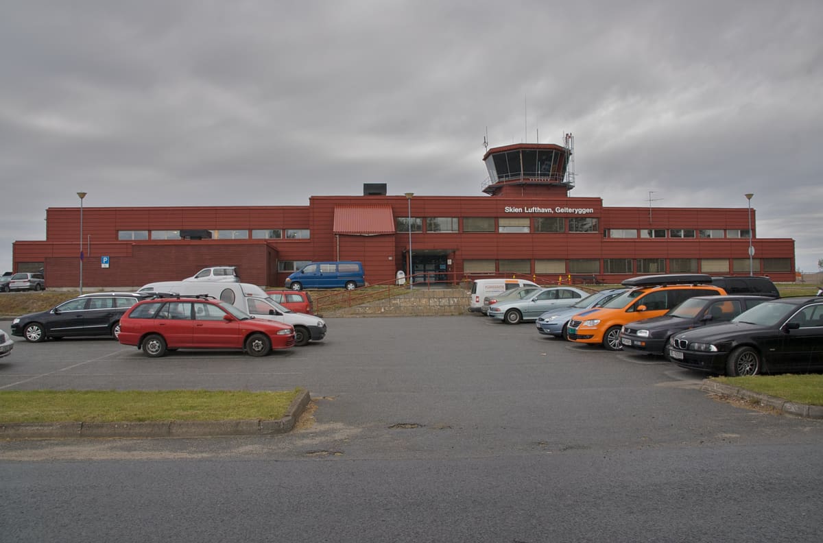 Det røde terminalbygget med tårnet på taket, sett fra parkeringsplassen